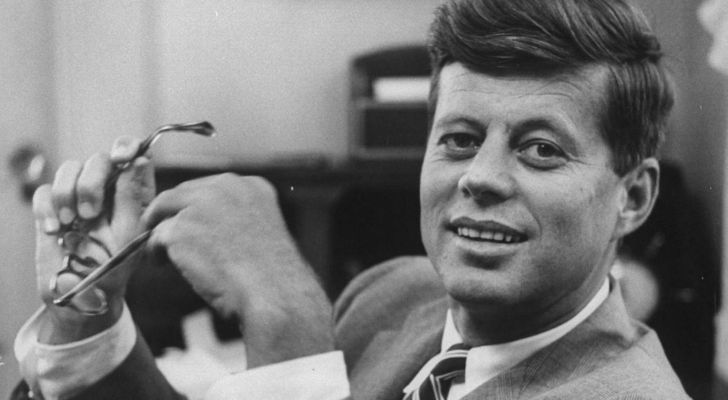 John f Kennedy holding a pair of glasses