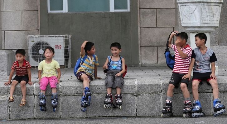 Children sitting on a wall wearing roller-skates
