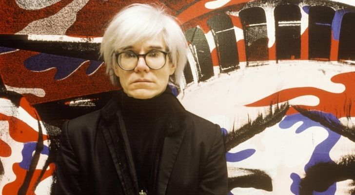 Andy Warhol with his iconic white hair and thick black framed glasses